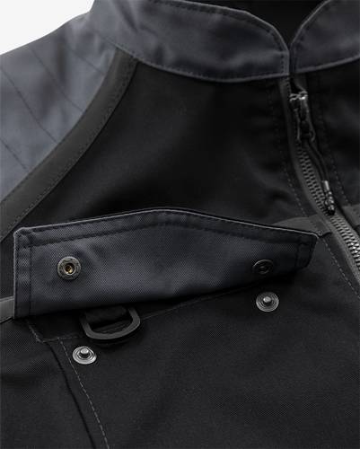 Nahaufnahme einer dunklen Stoff-Jacke mit Reißverschluss- und Knopfdetails, die die Nähte und Materialtextur hervorhebt.
