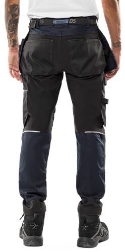 Eine Person, die dunkle Cargohosen mit sichtbaren Taschen an den Seiten trägt.