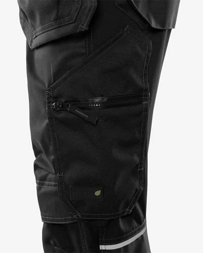 Nahaufnahme einer schwarzen Hose mit Tasche, Reißverschluss und sichtbarem Markenetikett 'FRISTADS' auf der Taschenklappe.