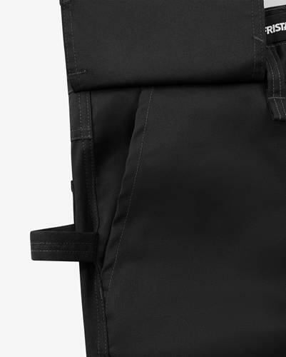 Eine Nahaufnahme einer schwarzen Stofftasche, die eine Naht und einen Riemen auf der linken Seite zeigt und dabei ihre Textur und Handwerkskunst hervorhebt.