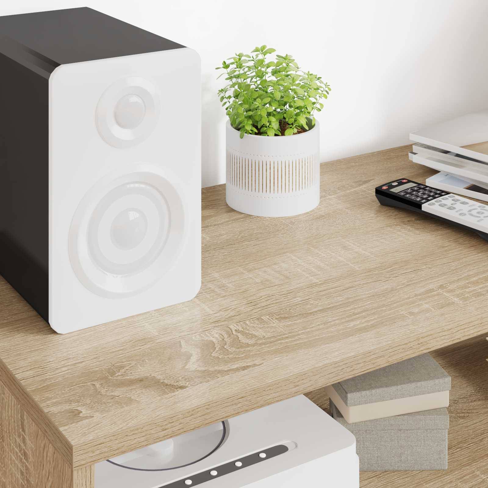Ein weißer Lautsprecher mit schwarzen Akzenten auf einem Holzschreibtisch neben einer grünen Topfpflanze und Büromaterialien, die ein modernes Workspace-Setup schaffen.