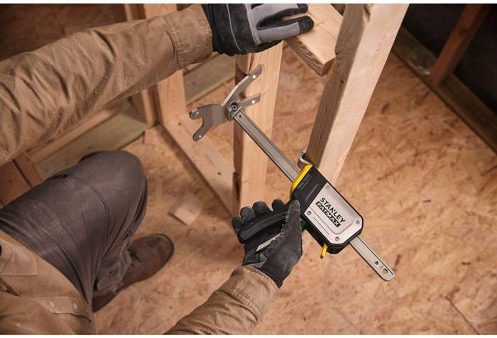 Eine Person, die eine Stanley-Triggerklammer verwendet, um Holzbretter zusammenzuhalten und eine Zimmermannsarbeit auf einer Holzoberfläche zu demonstrieren.