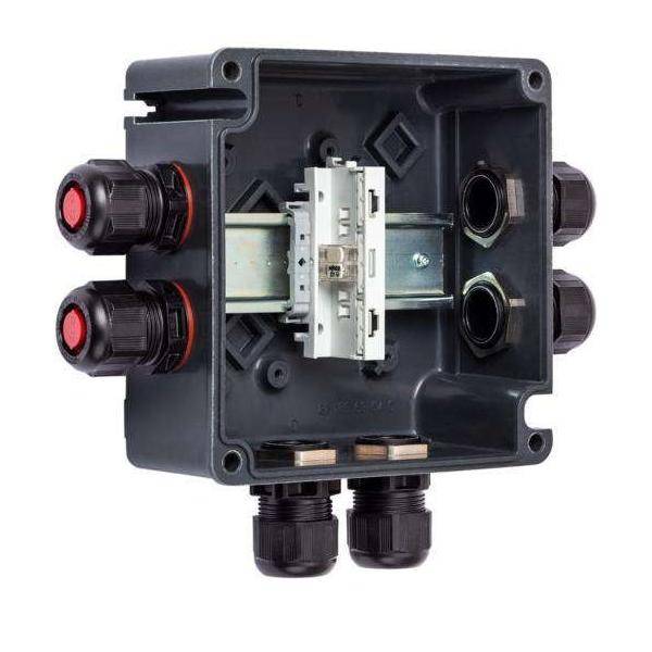 Eine elektrische Verteilerdose mit mehreren Kabeleinführungen und einer Hutschiene zur Montage von Schaltgeräten.