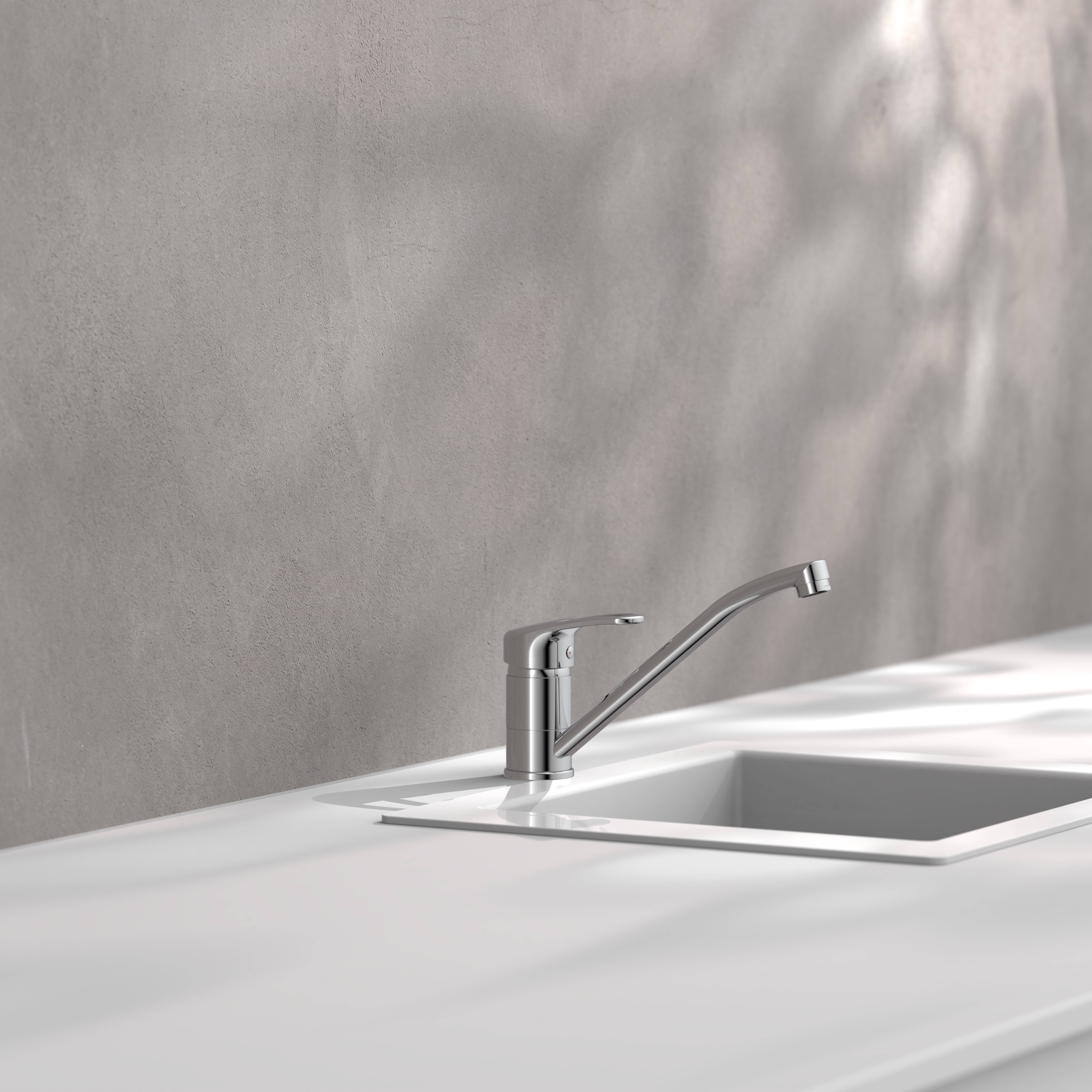 Ein minimalistisches Küchenspülbecken mit einem Chromhahn vor einer hellgrauen Wand, das weiche, getupfte Lichter schattiert.