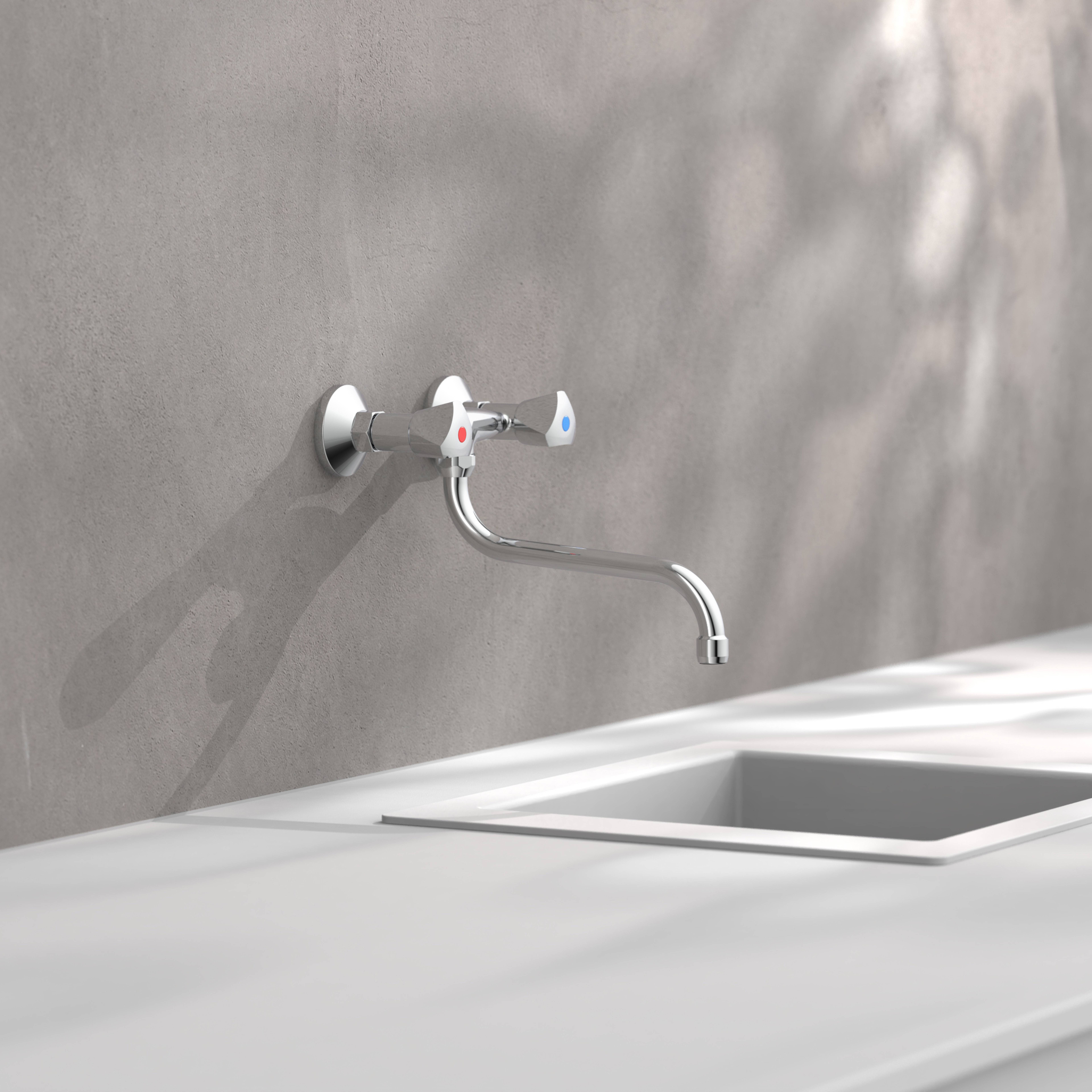 Ein wandmontierter Chromwasserhahn mit separaten Warm- und Kaltventilen erstreckt sich über ein weißes Waschbecken an einer glatton grauen Wand.