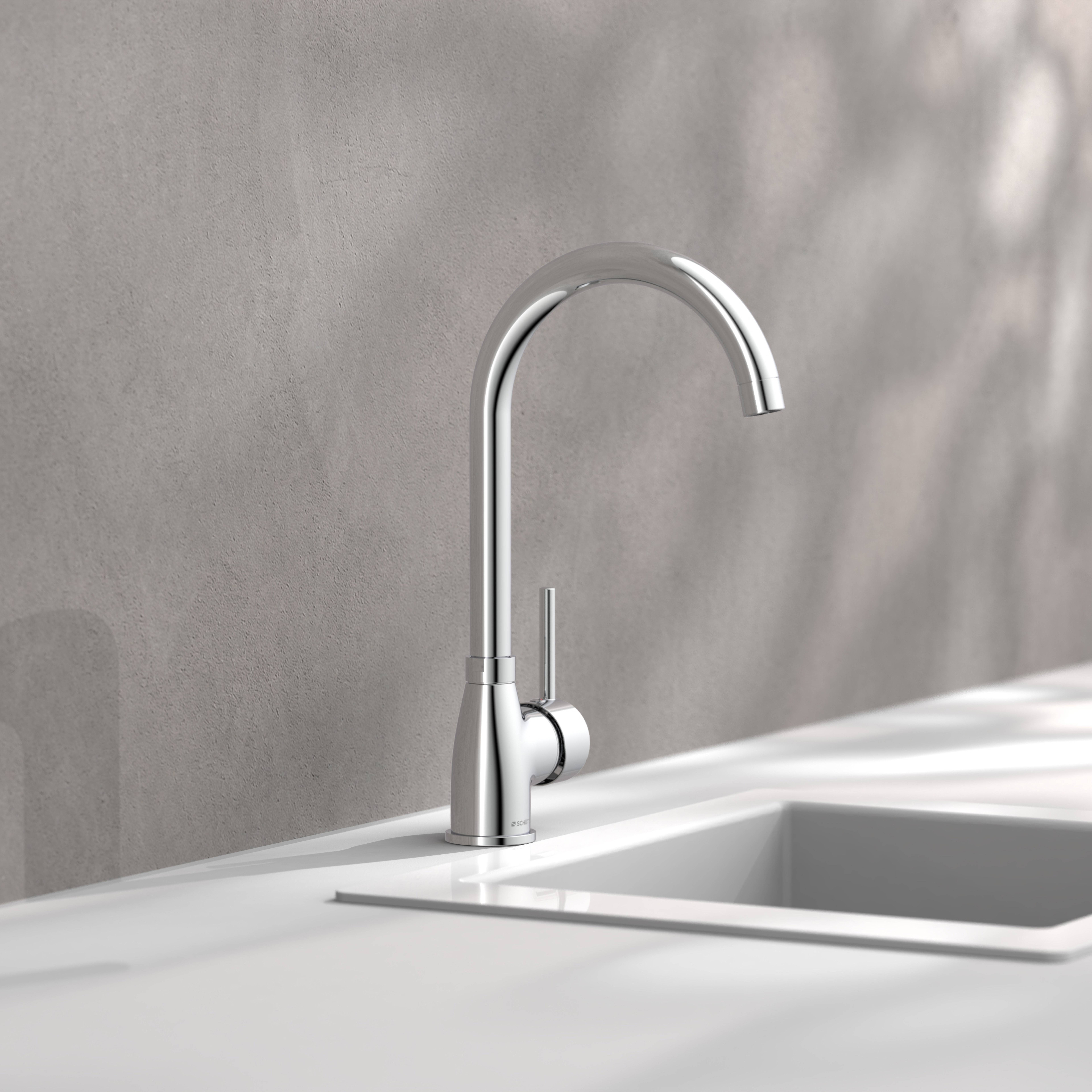 Ein moderner silberner Wasserhahn mit schlankem Design ist über einem weißen rechteckigen Waschbecken montiert und vor einem hellgrauen Wandhintergrund angebracht.