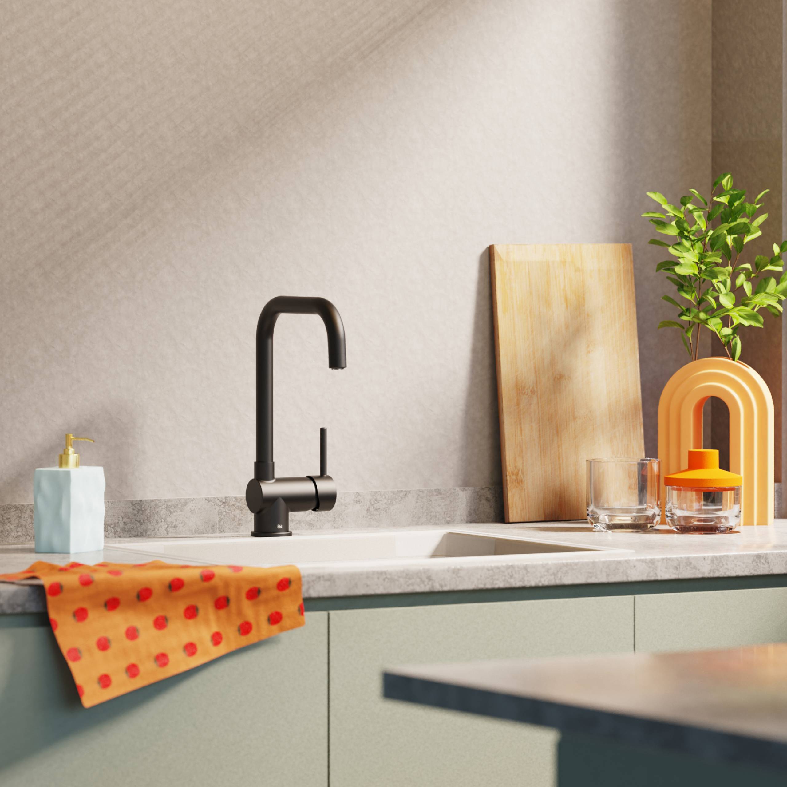 Moderne Küche mit einem schwarzen Wasserhahn, einem hölzernen Schneidebrett und einem leuchtend orangefarbenem Geschirrabtrockner neben einer kleinen Pflanze in der Nähe eines Spülbeckens.