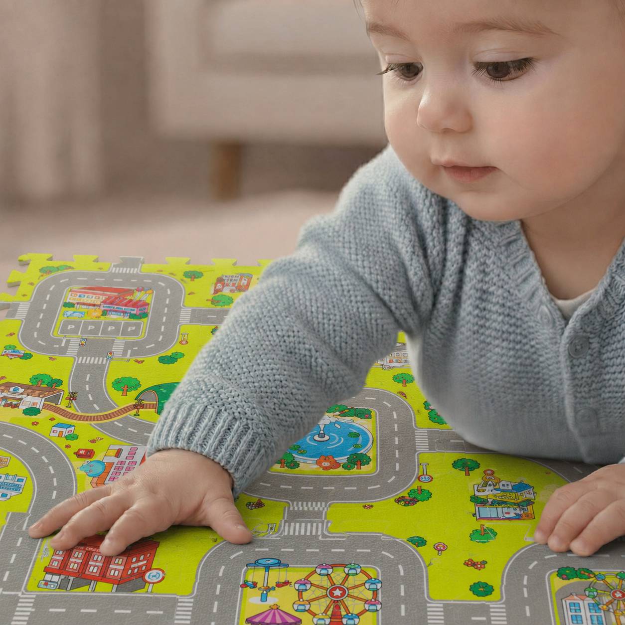 Kleinkind in einem blauen Pullover spielt mit einer bunten Straßen- und Stadt-Spielmatte und greift mit einer Hand über die Matte.