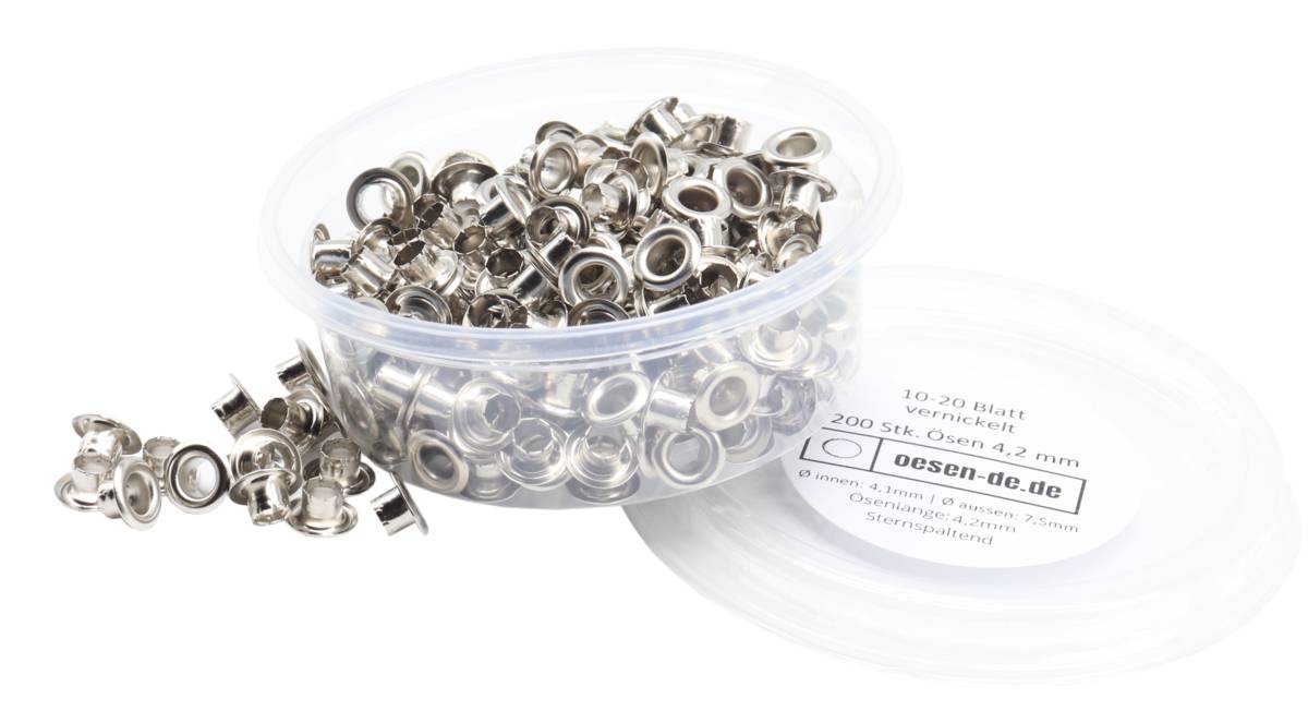 Ein Haufen metallischer Ösen in einem Plastikbehälter mit einem teilweise sichtbaren Verpackungsetikett, auf dem beschreibender Text auf Deutsch zu sehen ist.