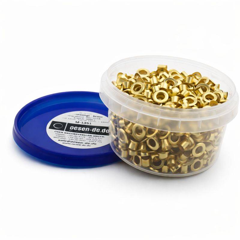 Ein Kunststoffbehälter gefüllt mit goldfarbenen Metalloesen, neben einem blauen Deckel mit einem Produktetikett, auf weißem Hintergrund.