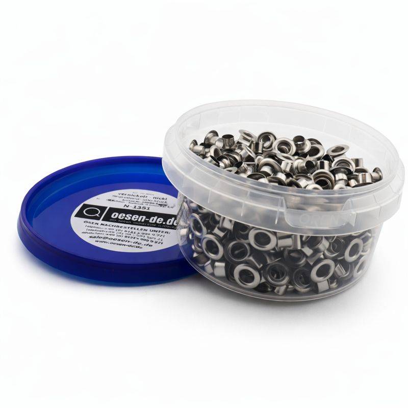 Ein durchsichtiger Behälter mit blauem Deckel enthält zahlreiche Metallösen, die für Stoff- oder Lederhandwerk verwendet werden, mit einem teilweise sichtbaren Etikett.