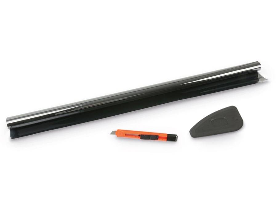 Eine Rolle schwarzer Film neben einem orangefarbenen Universalmesser und einem schwarzen Rakel-Werkzeug auf einer weißen Oberfläche, verwendet zum Tönen oder Verkleben.