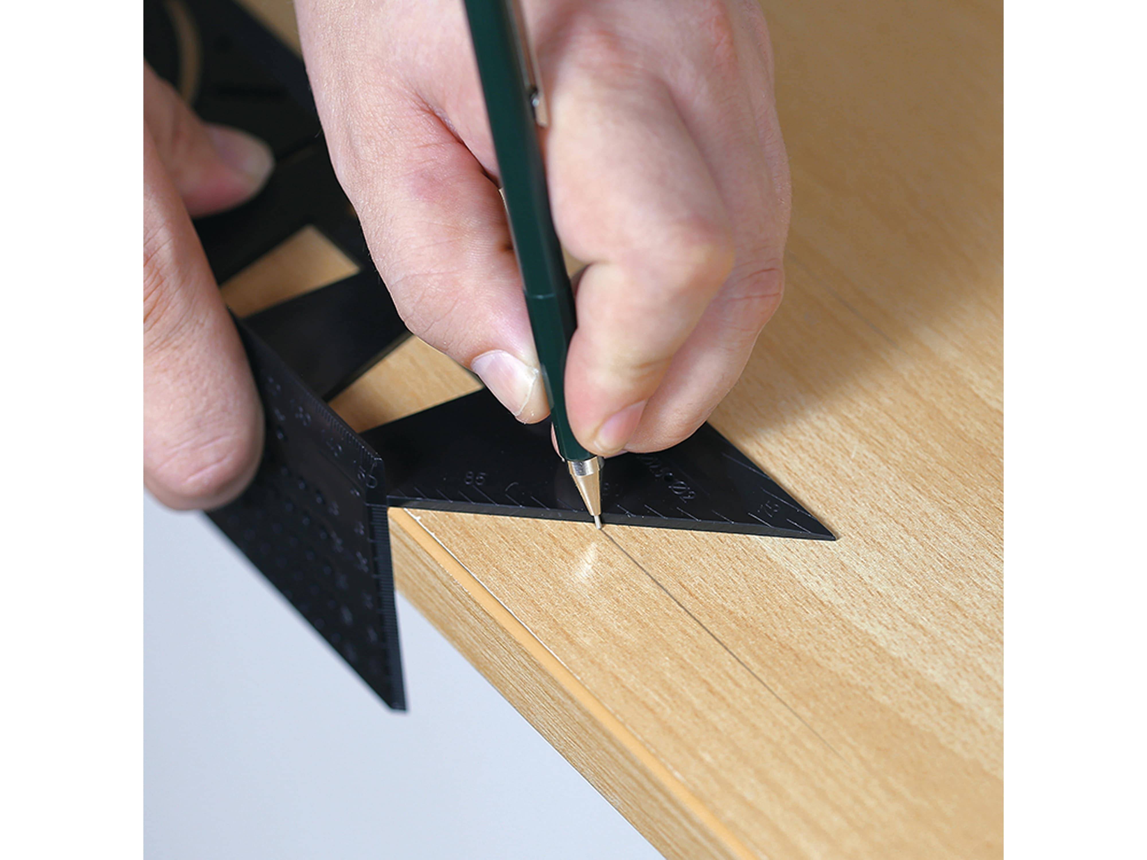 Eine Hand, die einen Bleistift hält, markiert eine Holzoberfläche mit einem schwarzen Dreiecklineal, was auf präzise Messung oder Zimmermannsarbeit hindeutet.