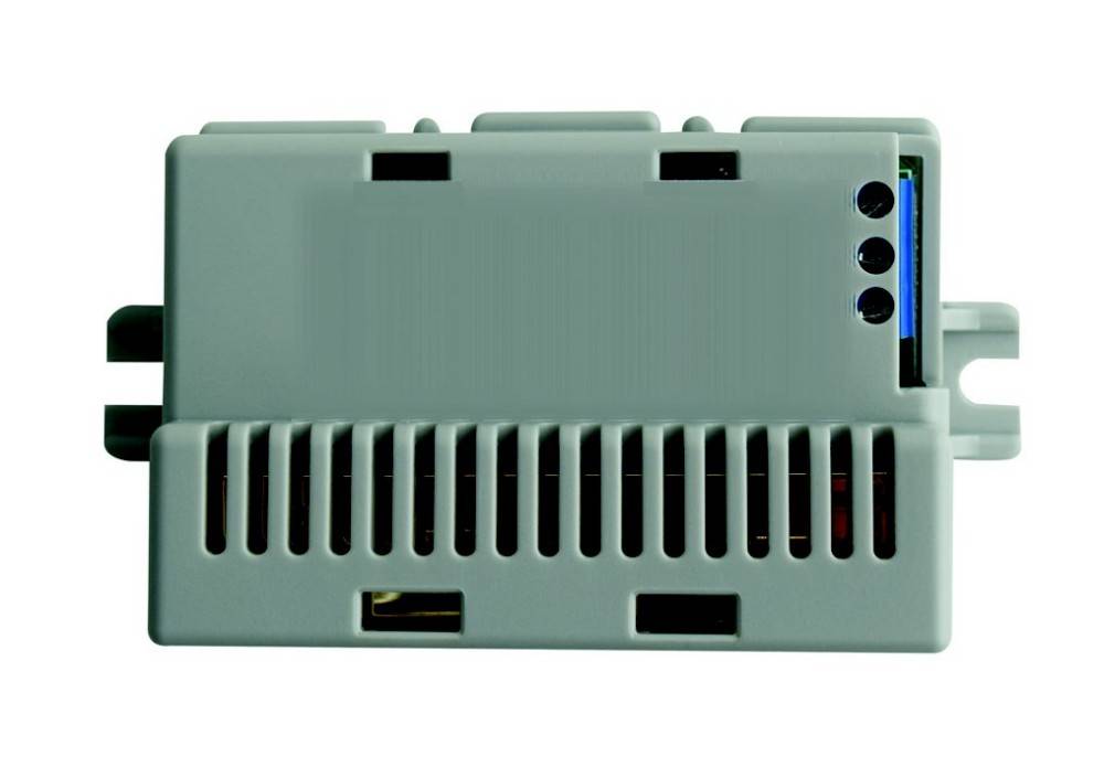 Eine Nahaufnahme eines grauen elektronischen Gerätekastens mit Lüftungsschlitzen und drei sichtbaren Anschlüssen an einer Seite.