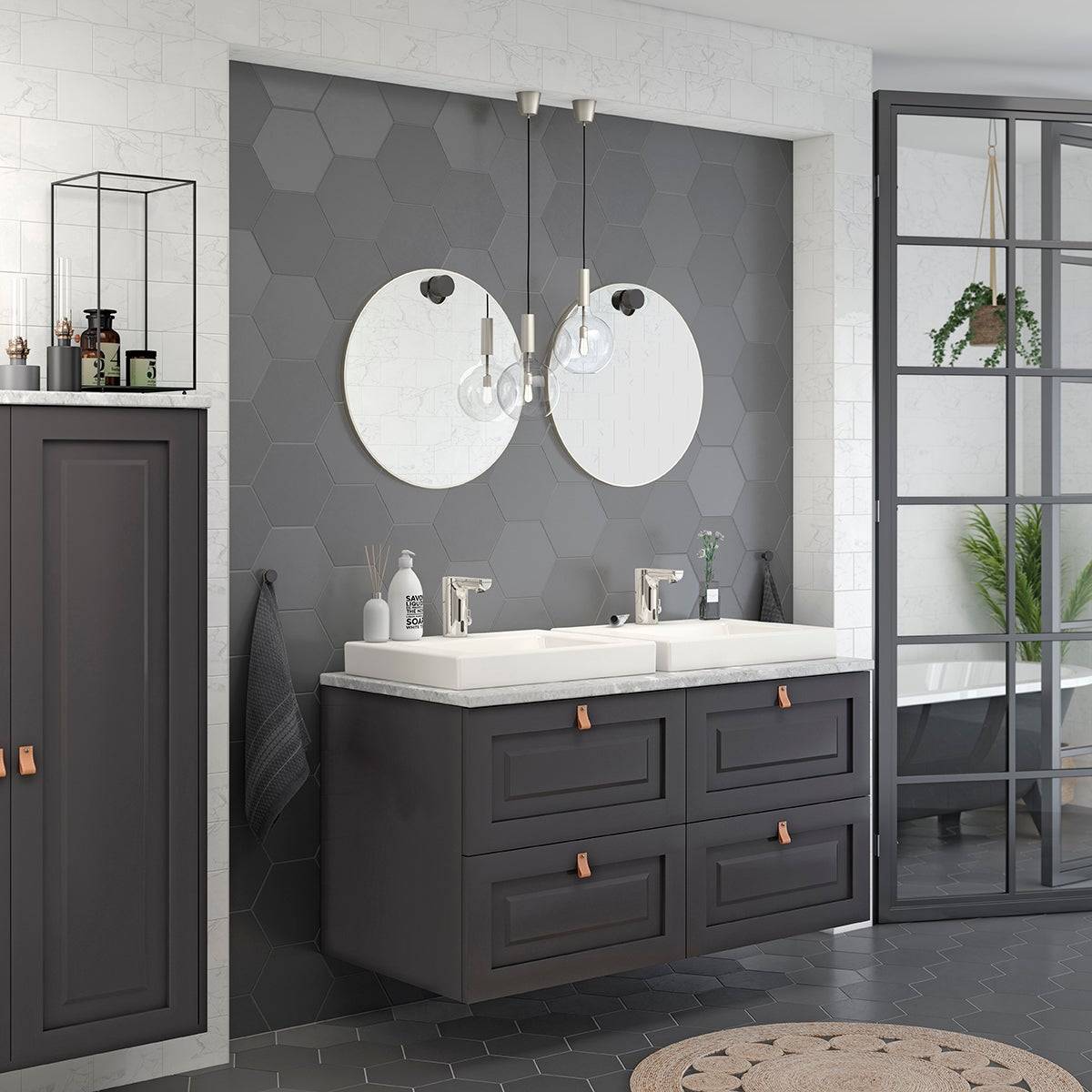 Modernes Badezimmer mit dunklem Doppelwaschbecken, runden Zwilllingsspiegeln, Pendelleuchten, sechseckiger Fliesenwand und Glastrennwand neben einer freistehenden Badewanne.