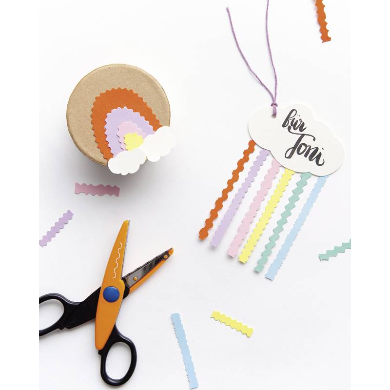 Eine Schere, eine Geschenkbox mit einem Regenbogen- und Wolkendesign und ein regenbogenfarbener Geschenkanhänger mit den Worten 