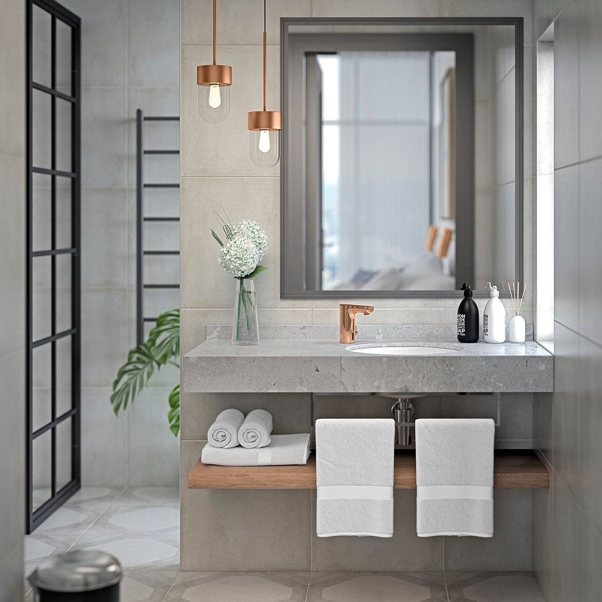 Modernes Badezimmer mit Betonwaschbecken, rundem Waschbecken, großem Spiegel, kupfernen Pendelleuchten, Handtüchern, aufgerollten Leinen und einer gläsernen Duschtür.