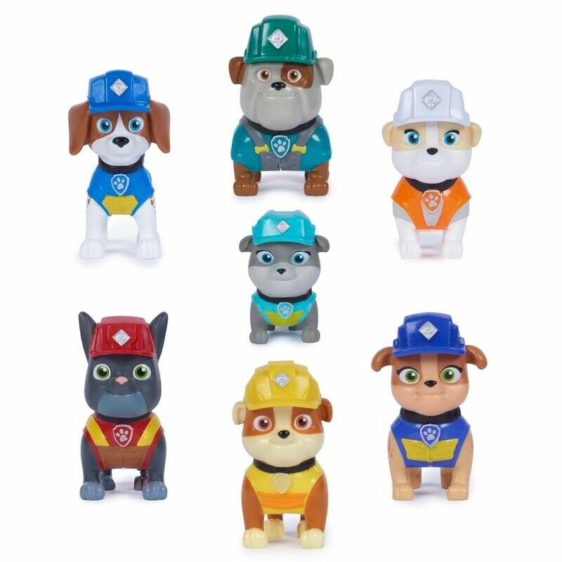 Sieben Paw Patrol Spielzeugfiguren auf weißem Hintergrund angeordnet, darunter Chase, Rocky, Rubble, Marshall, Zuma, Skye und Everest in farbigen Uniformen und Helmen.