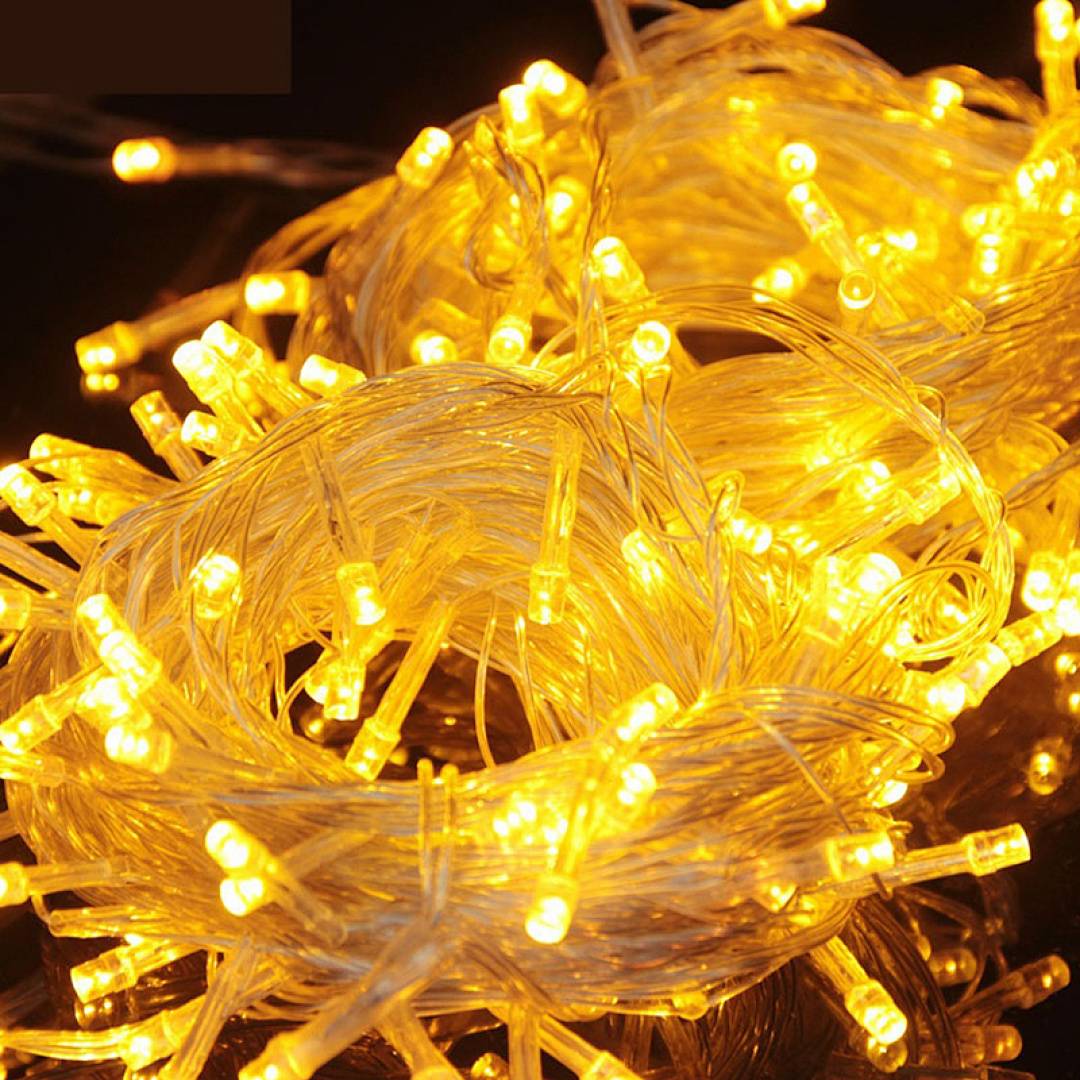 Aufgerollte Lichterketten mit warmem gelbem Glühen auf dunklem Hintergrund.