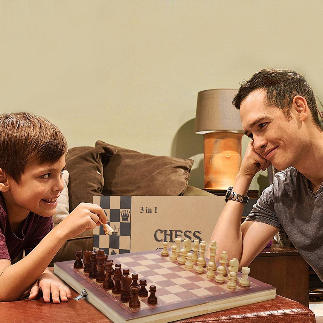 Ein Junge und ein erwachsener Mann spielen an einem Tisch Schach, lächeln und konzentrieren sich auf das Spiel in Innenräumen.