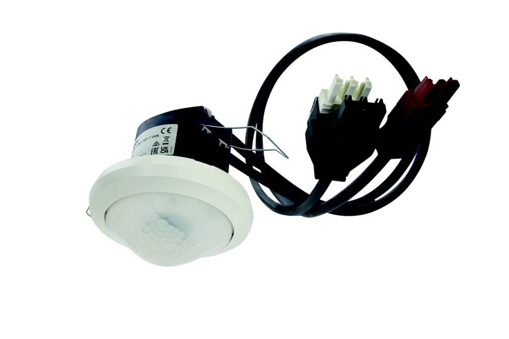 Ein deckenmontierter Bewegungssensor mit angeschlossener Verkabelung, entwickelt zur Bewegungserkennung in Innenräumen.