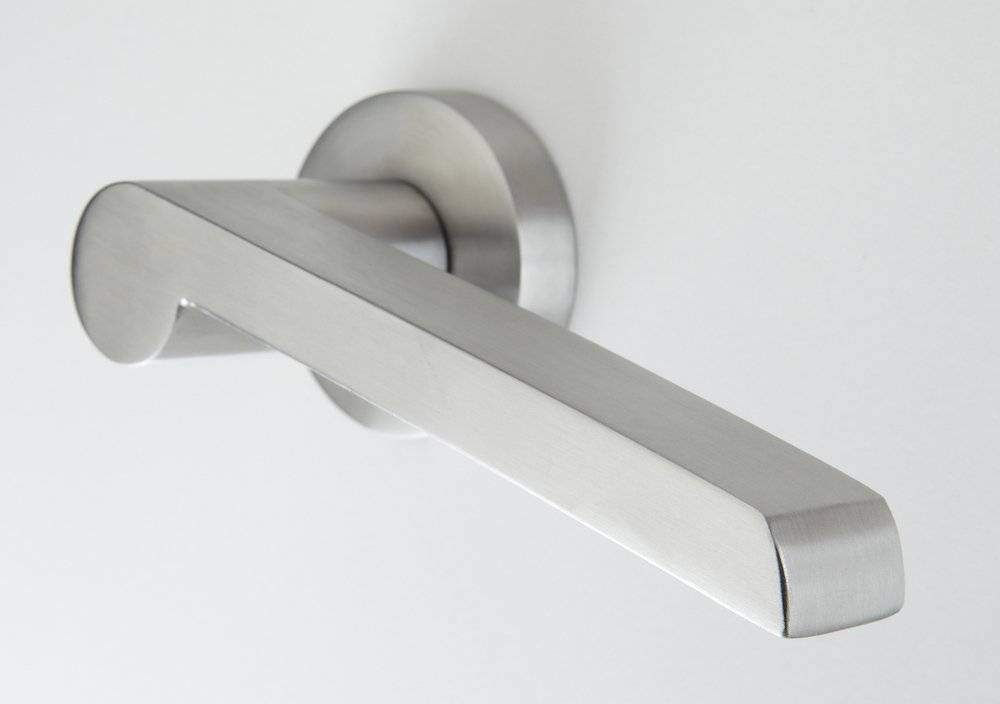 Eine Nahaufnahme eines modernen, silbernen Metallgriffs, der an einer schlichten weißen Tür angebracht ist.