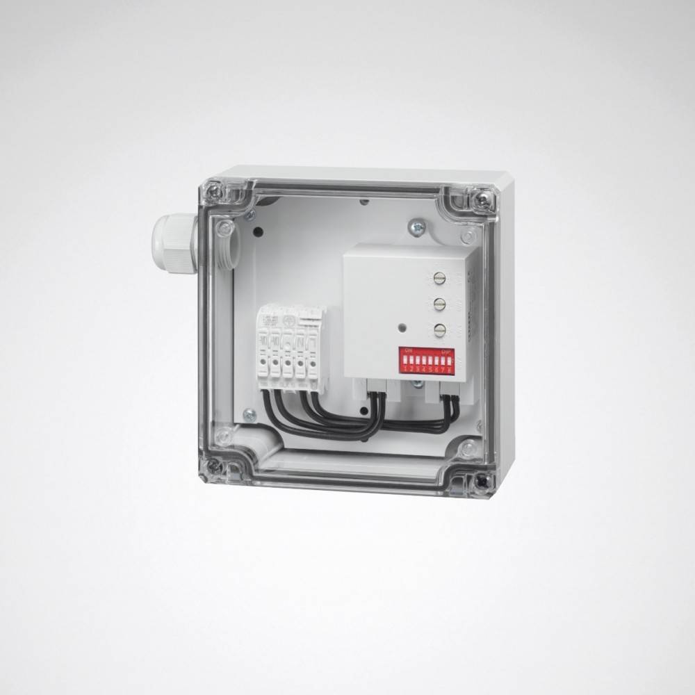 Eine graue elektrische Verteilerdose mit transparentem Deckel, die Kabelverbindungen und eine rote Schaltkomponente im Inneren zeigt, an einer Wand montiert.