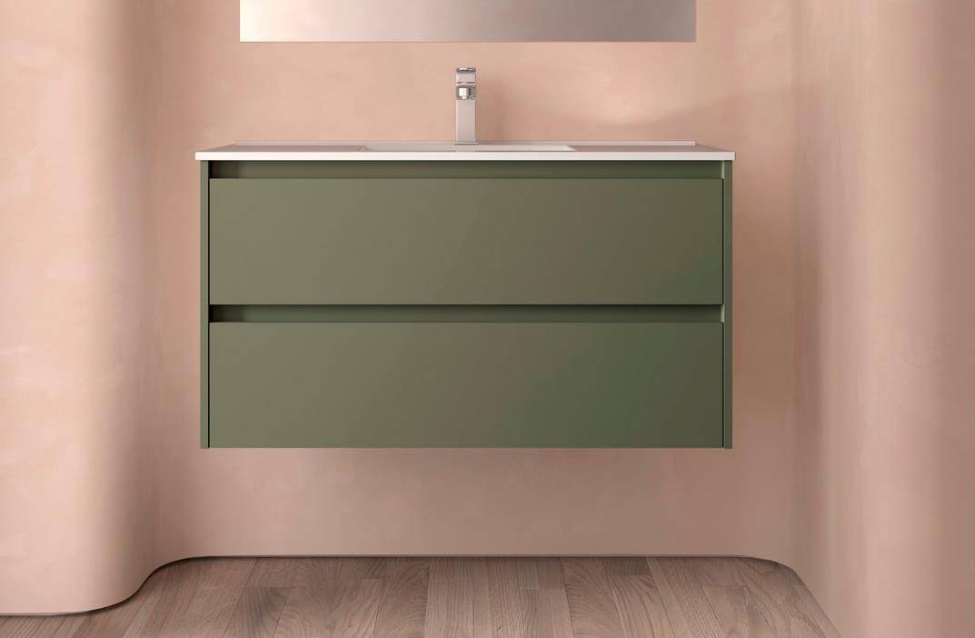 Modernes olivgrünes, wandmontiertes Badezimmermöbel mit integriertem Waschbecken und Spiegel darüber, vor einer rosafarbenen Wand und Holzboden.