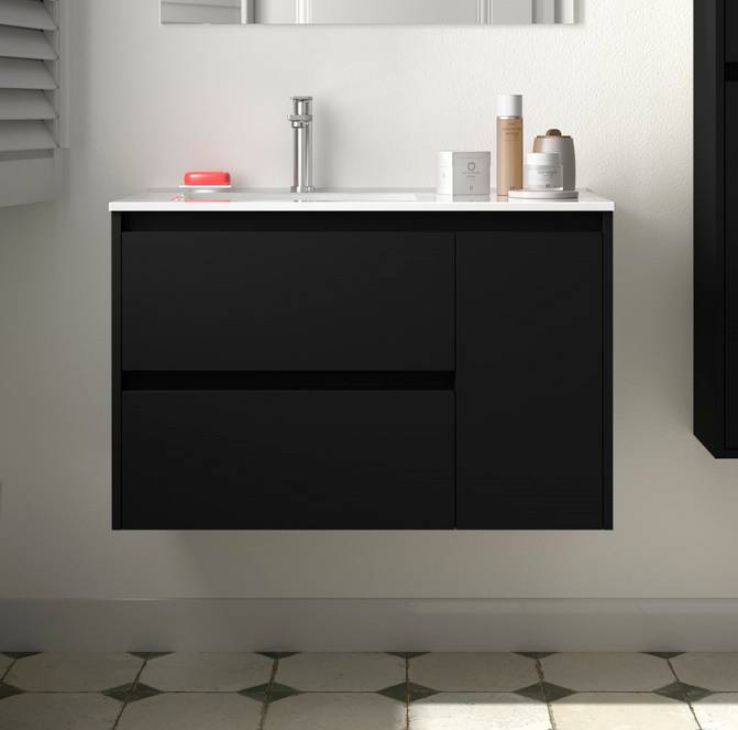 Schwarzer, wandmontierter Badezimmerschrank mit weißer Arbeitsplatte, Waschbecken, Armatur und Toilettenartikeln vor einer hellen gefliesten Wand.