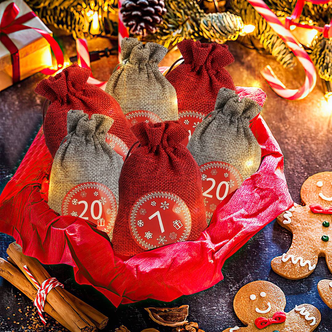 Weihnachtsgeschenkkorb mit sechs Jutesäckchen mit Kordelzug, beschriftet mit '1' bis '20', umgeben von festlicher roter Verpackung, Lebkuchenplätzchen, Zimtstangen und Weihnachtsdekoration.