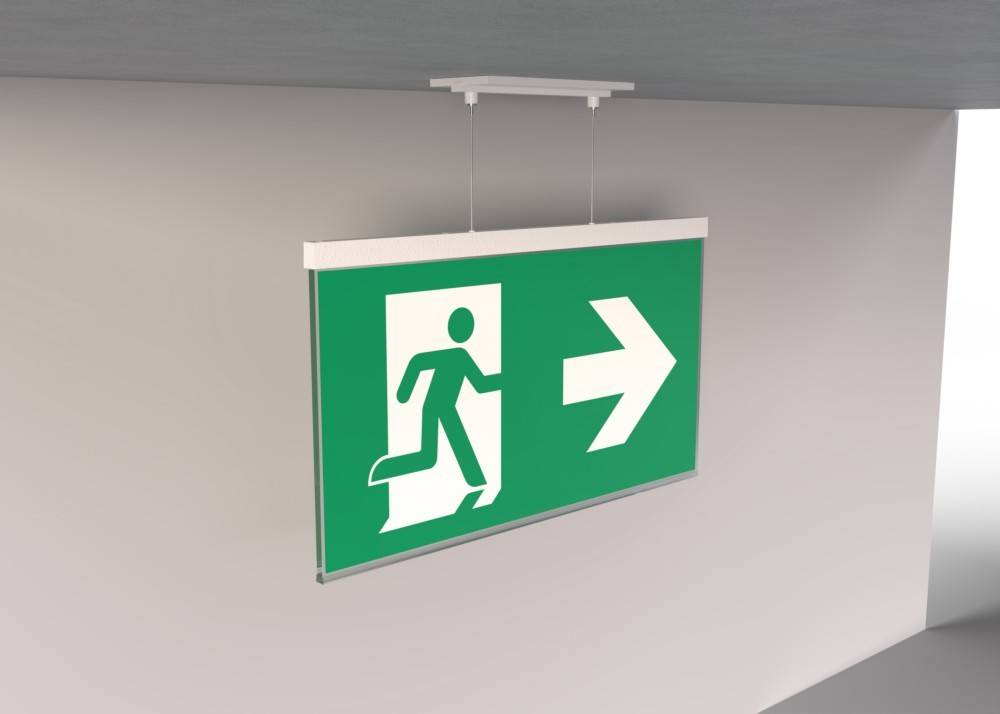 Notausgang-Schild über einer Tür mit einer weißen laufenden Figur und einem Pfeil, der nach rechts zeigt, auf grünem Hintergrund, der die Richtung zum Ausgang anzeigt.