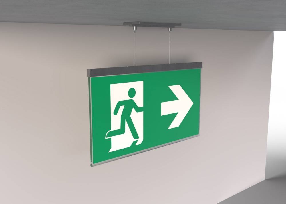 Notausgang-Schild mit grünem Hintergrund, auf dem eine Figur zu einem nach rechts weisenden Pfeil läuft.