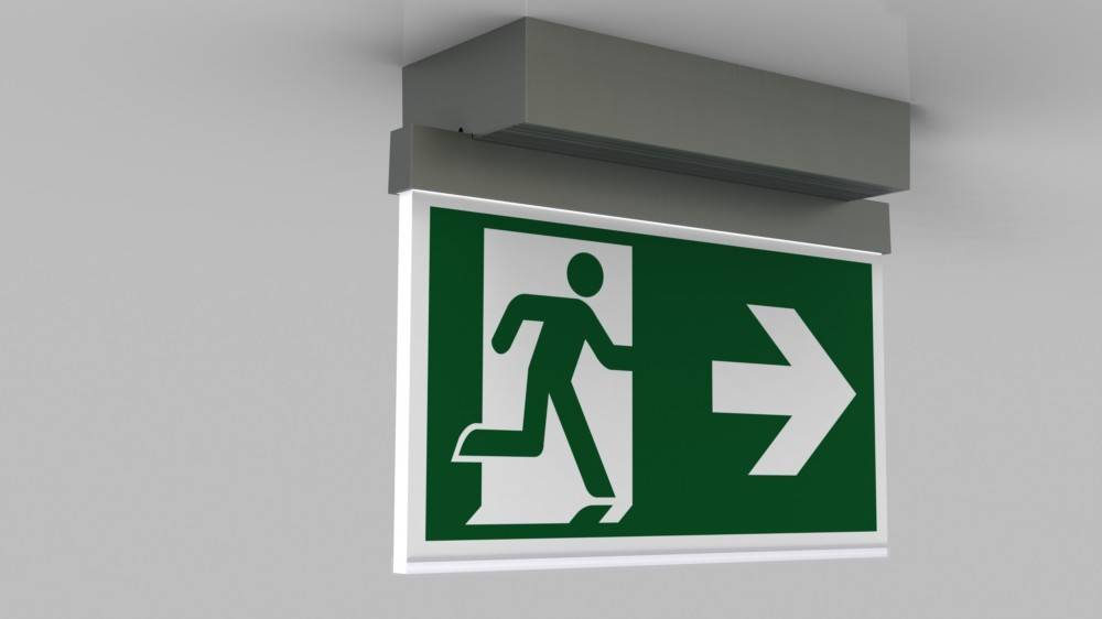 Notausgangsschild mit einer laufenden Figur und einem Pfeil, der nach rechts weist und die Richtung zum nächstgelegenen Ausgang anzeigt.