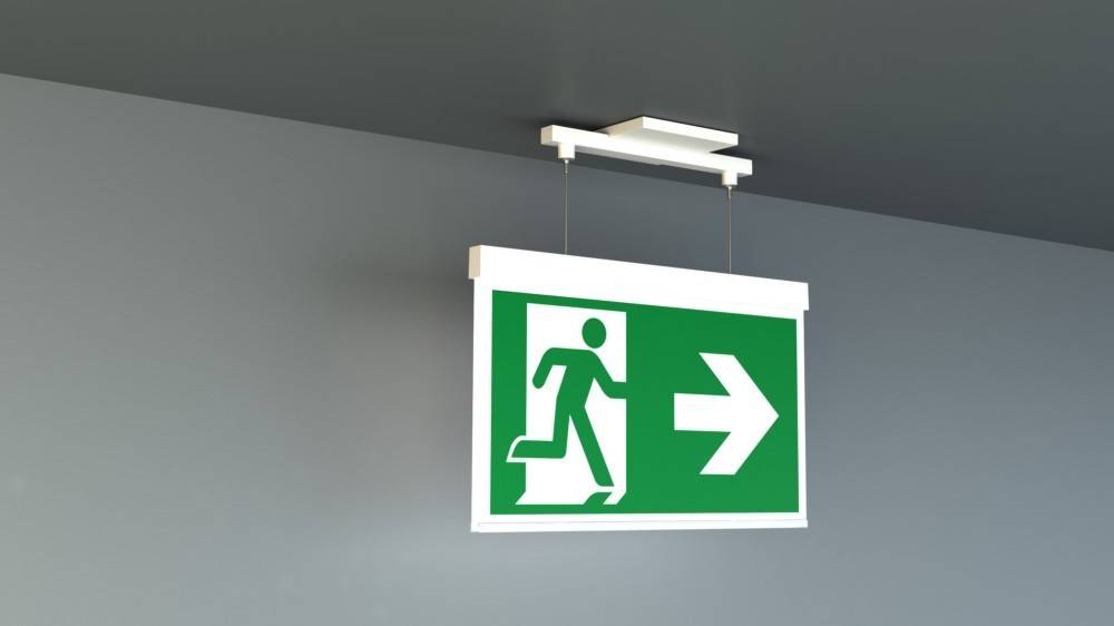 Rettungszeichenschild mit einer laufenden Figur und einem nach rechts weisenden Pfeil auf grünem Hintergrund, der die Richtung zum Notausgang anzeigt.