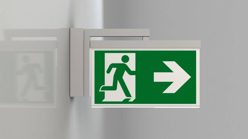 Ein grünes Notausgangsschild mit einer weißen Figur, die nach rechts läuft und die Richtung zum Ausgang anzeigt.