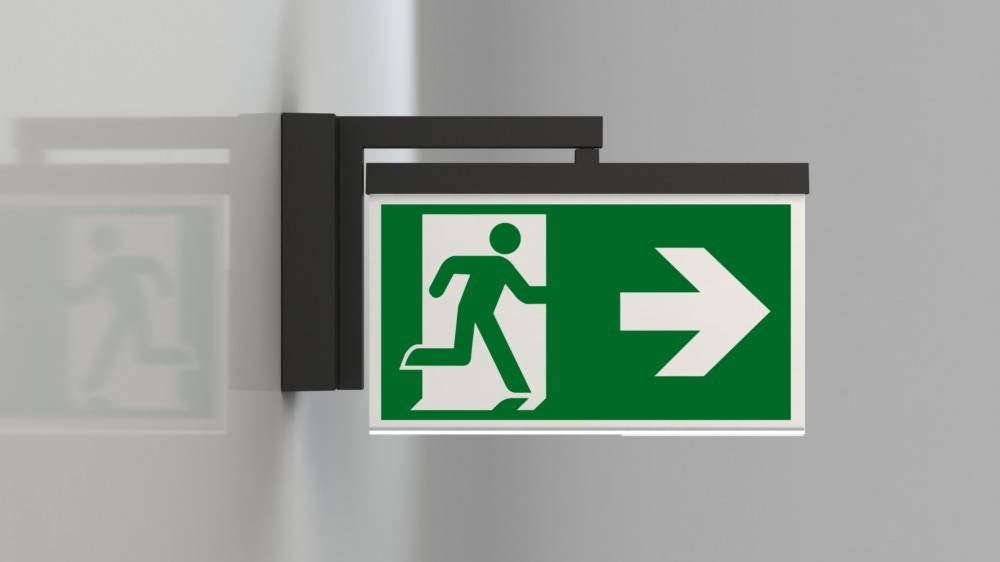 Ein grünes Notausgangsschild mit einer laufenden Figur und einem nach rechts weisenden Pfeil zeigt die Evakuierungsroute an.