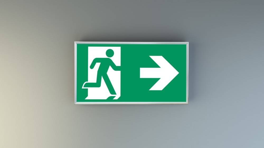 Ein grünes Notausgangsschild mit einer laufenden Figur und einem nach rechts weisenden Pfeil, der die Richtung zum nächstgelegenen Ausgang anzeigt.