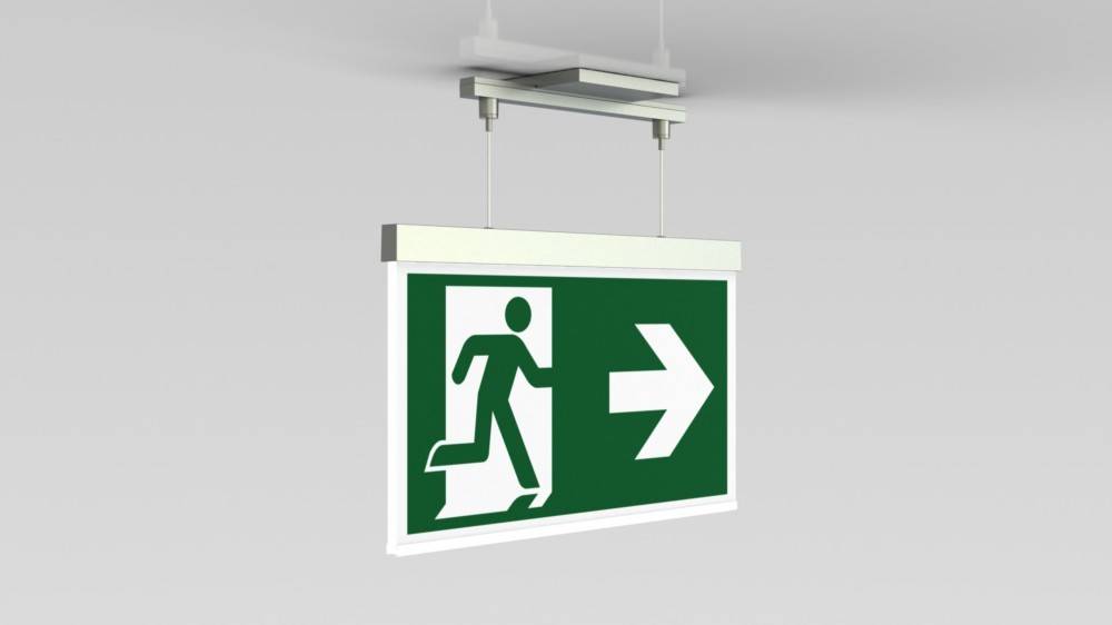 Ein Fluchtzeichenschild mit grünem Hintergrund zeigt eine laufende Person und einen nach rechts zeigenden Pfeil, der die Richtung zum Ausgang angibt.