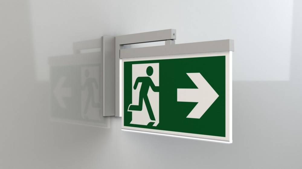 Notausgangsschild mit einer Figur, die durch eine Tür läuft, mit einem Pfeil, der nach rechts zeigt und die Richtung zum Ausgang angibt.