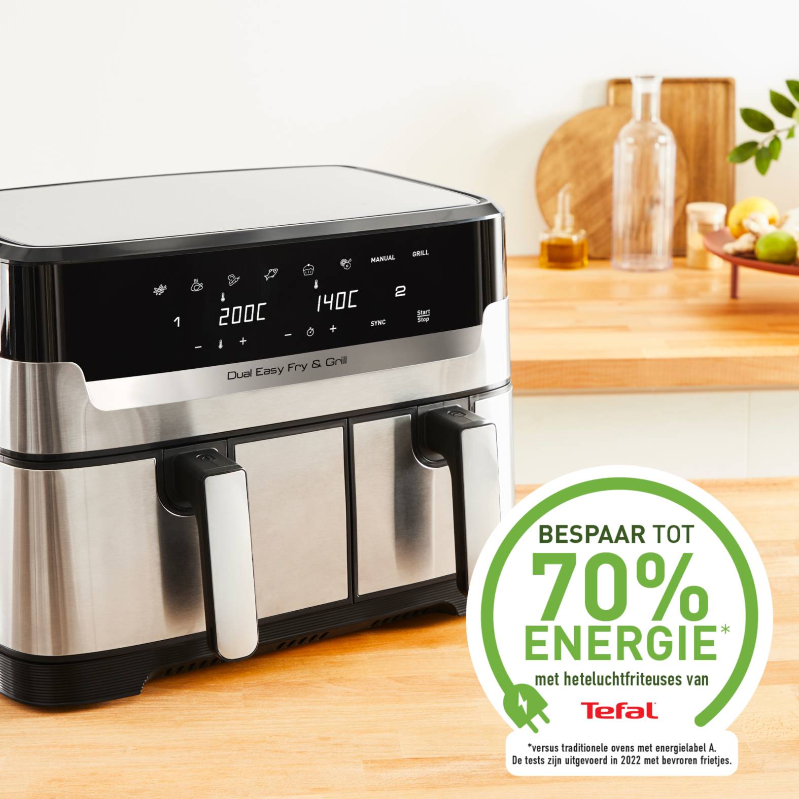 Edelstahl-Doppel-Heißluftfritteuse von Tefal mit digitaler Steuerung auf einer Küchenarbeitsplatte, plus ein grünes Abzeichen mit der Aufschrift „Bespaar tot 70% energie" und „Tefal"".