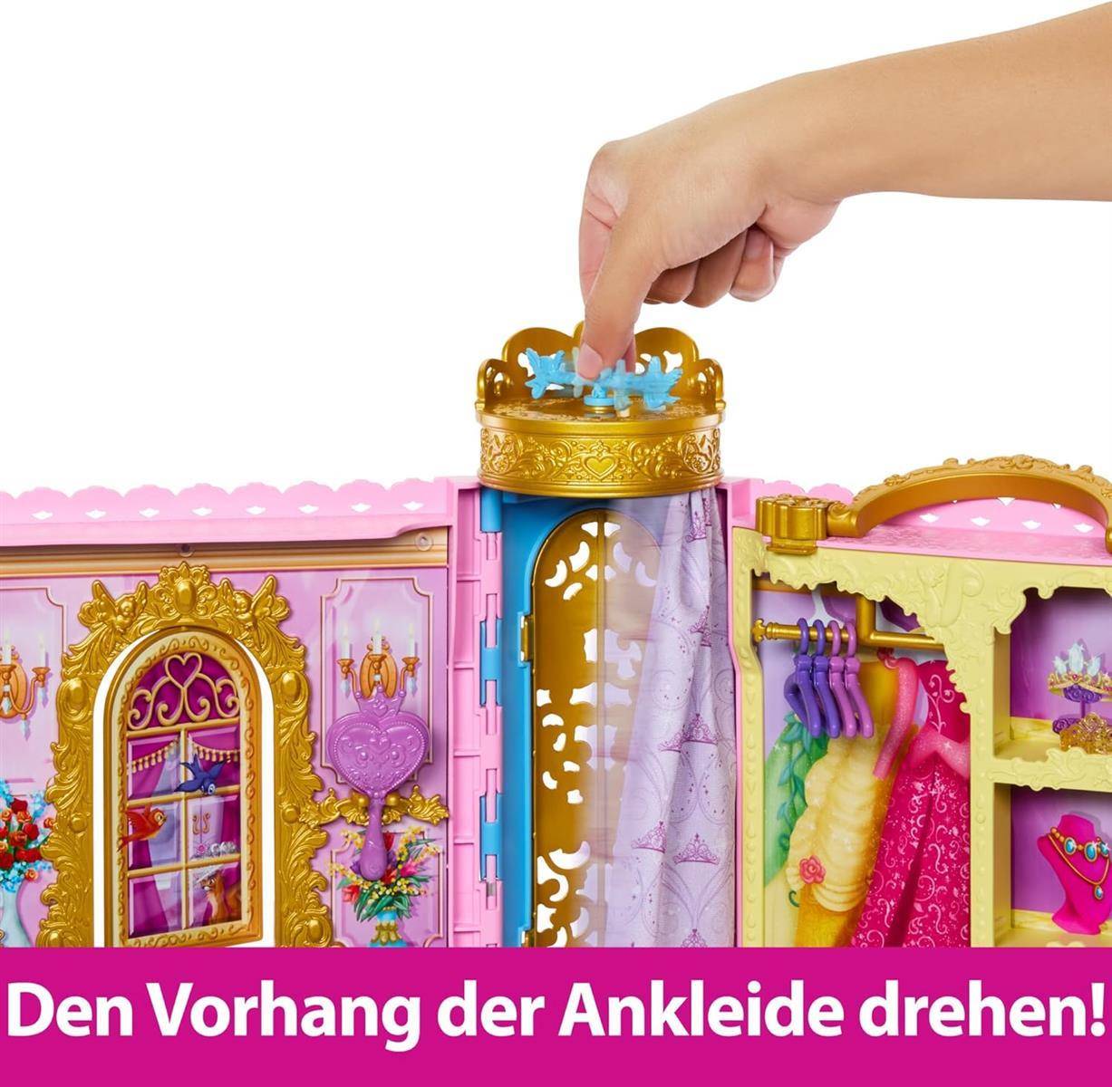 Eine Hand dreht an einem Drehknopf oben an einem Spielzeugkleiderschrank, um den Vorhang in einem rosa-goldenen Puppenumkleideraum zu drehen.