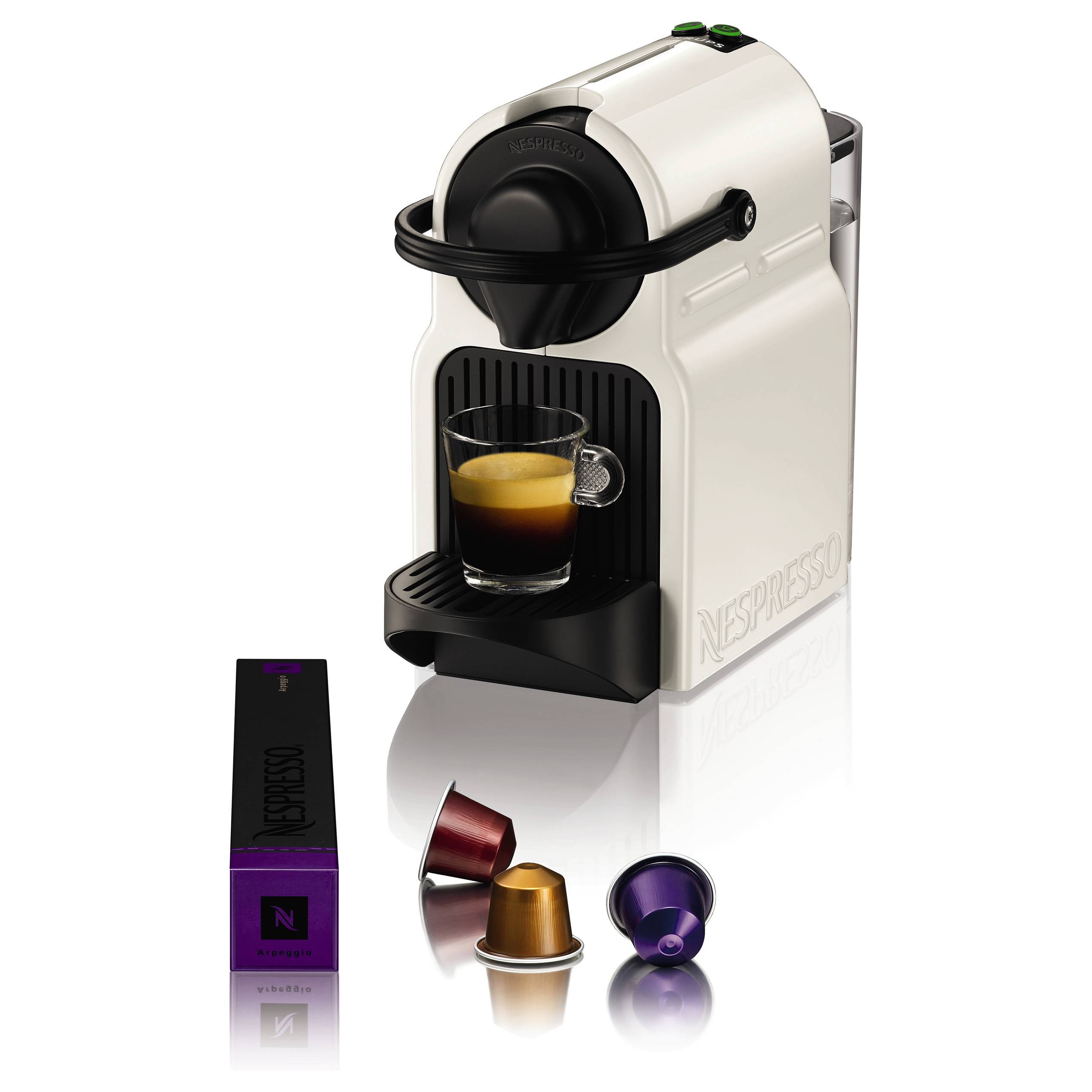 Eine weiße Nespresso-Kaffeemaschine, die Espresso in eine Tasse brüht, mit drei farbigen Kaffeekapseln und einer Schachtel daneben.