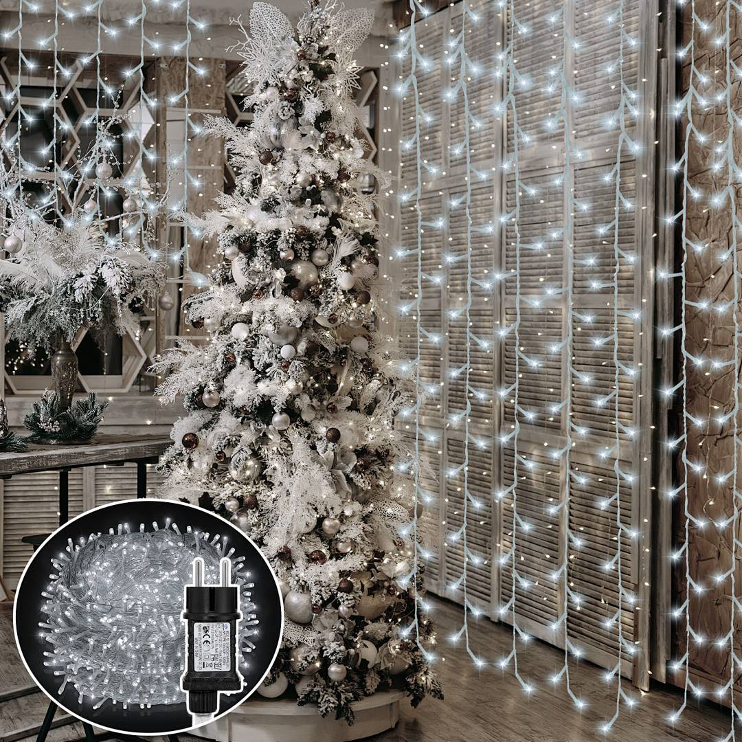 Dekorierter weißer Weihnachtsbaum mit Lichtern und Schmuck in einem Zimmer, neben einem Fenster und einer Wand mit hängenden Lichterketten; die Vergrößerung zeigt eine Steckdosen-Feenlichterkette.