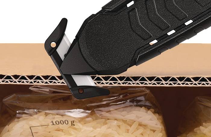Nahaufnahme eines schwarzen Utility-Messers, das eine Pappschachtel durchschneidet, in der sich ein durchsichtiger Reisbeutel mit der Aufschrift „1000 g