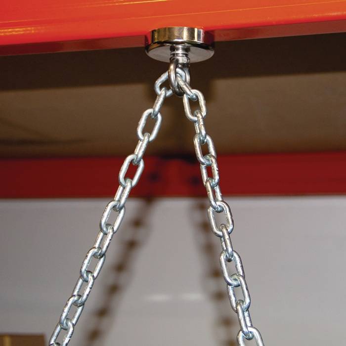 Eine Nahaufnahme einer Metallkette, die an einem Magnethaken befestigt ist, der an einem Stahlträger hängt und Stärke und Unterstützung in einer industriellen Umgebung signalisiert.