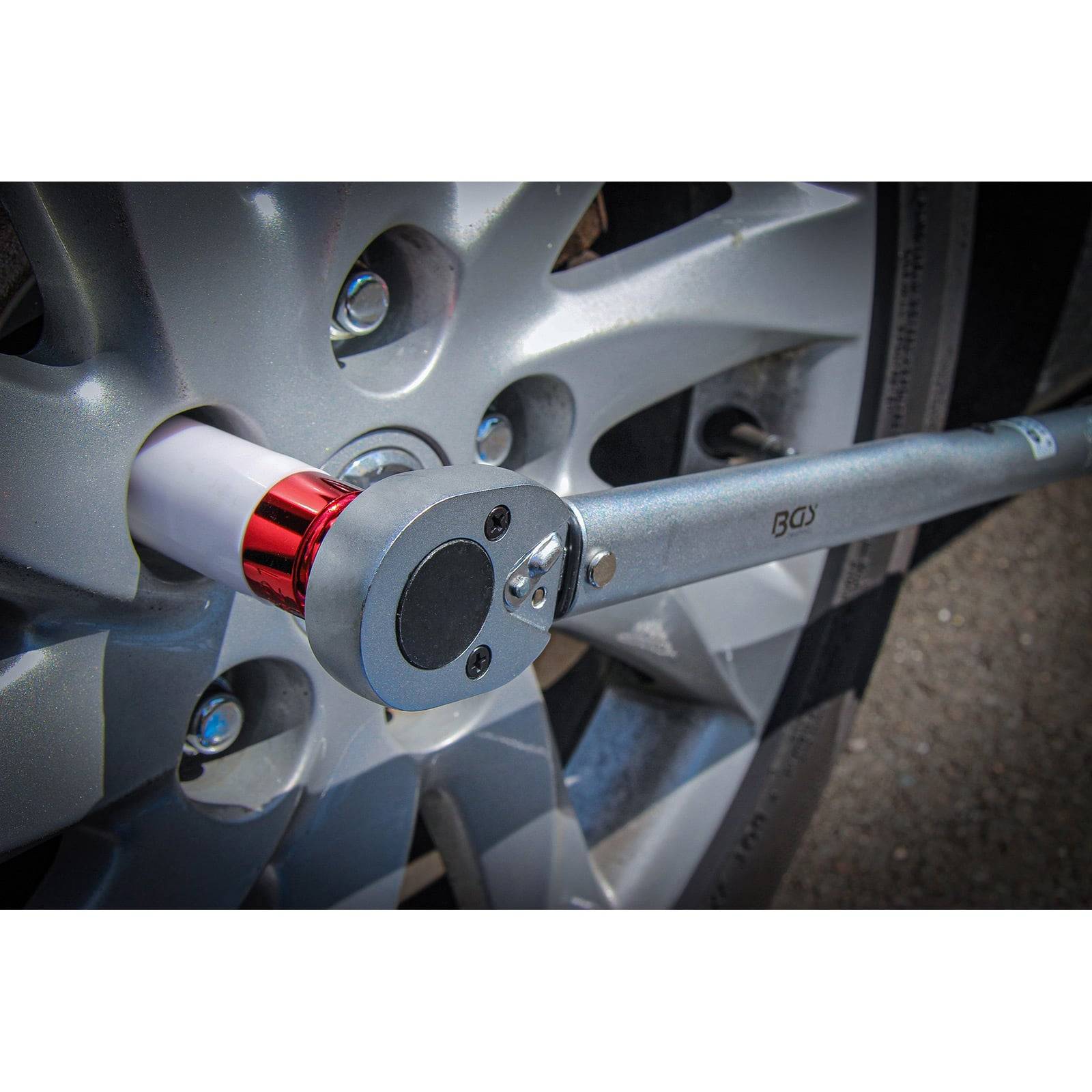 Ein Drehmomentschlüssel zieht eine Radmutter an einem Autrad fest.