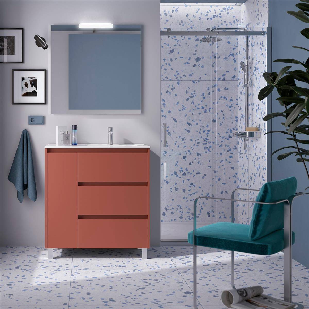 Modernes Badezimmer mit korallenfarbenem Waschtisch, Wandspiegel und Leuchte, gemusterter Fliesendusche und türkisfarbenem Stuhl neben einer Pflanze.