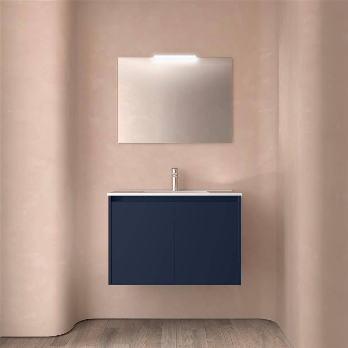 Modernes Badezimmer-Waschtisch mit einem marineblauen schwebendem Schrank, weißem Waschbecken und Armatur, rechteckigem Spiegel und Holzoptik-Boden vor beigefarbenen Wänden.