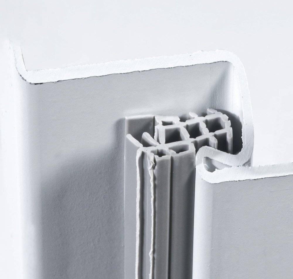 Eine Nahaufnahme der Kante eines weißen Panels, die seine geschichtete Struktur mit gewellten Linien und einer strukturierten Oberfläche zeigt, was die Materialzusammensetzung veranschaulicht.