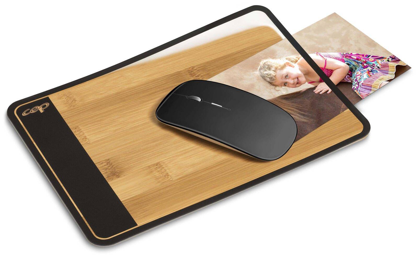 Computermausunterlage mit einer schwarzen Maus auf einer Holzmaserungsoberfläche mit einem Fotoeinsatz eines lächelnden Kindes in der Ecke.